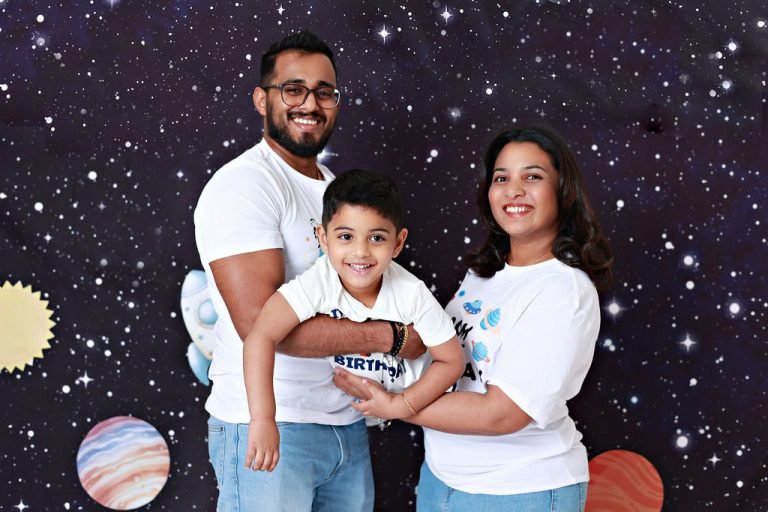 Family of three in matching white T-shirts on a space-themed backdrop, family photoshoot in Doha
