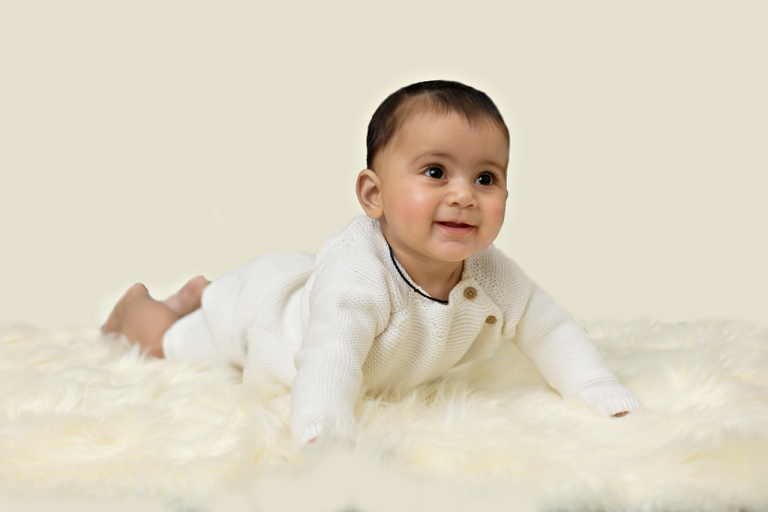 Baby crawling on a white fur rug in a cream outfit