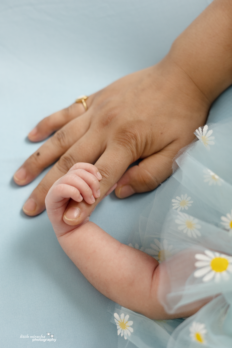 Parent's hand holding a newborn baby's tiny hand, close-up detail