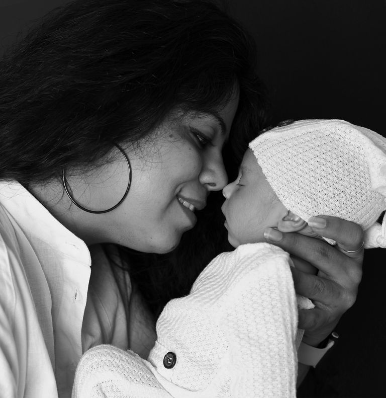 Black and white portrait of a mother kissing her newborn baby