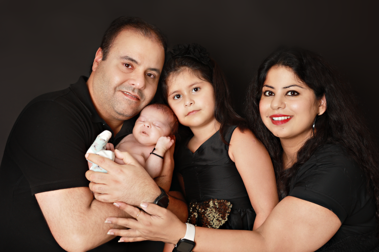 Parents and older sister holding their newborn baby, family newborn portrait in Doha