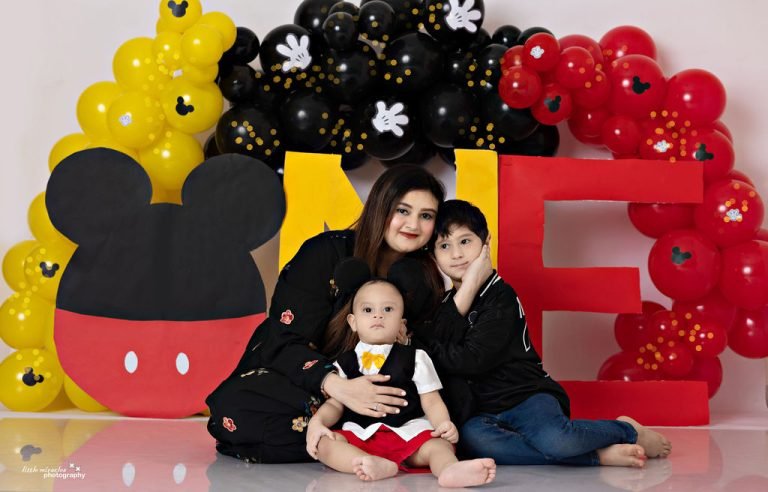 Mother with her sons at a Mickey Mouse first birthday setup