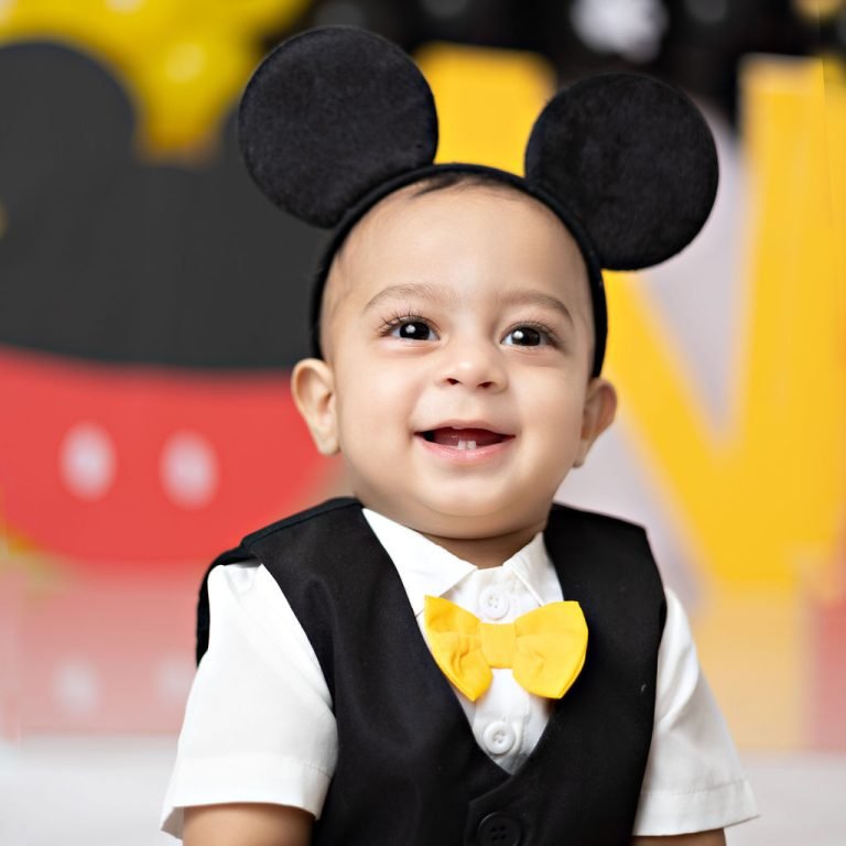Smiling one-year-old boy wearing Mickey Mouse ears, close-up portrait
