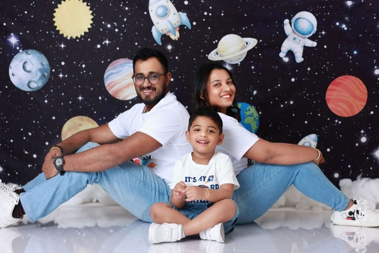 Family sitting together on a space-themed backdrop with planets and astronauts