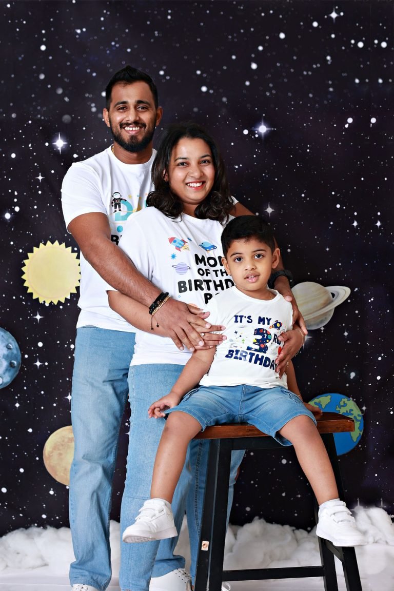 Family of three on a starry backdrop, boy on a stool in a birthday T-shirt